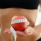 Fit-woman-holding-apple-wrapped-with-measuring-tape